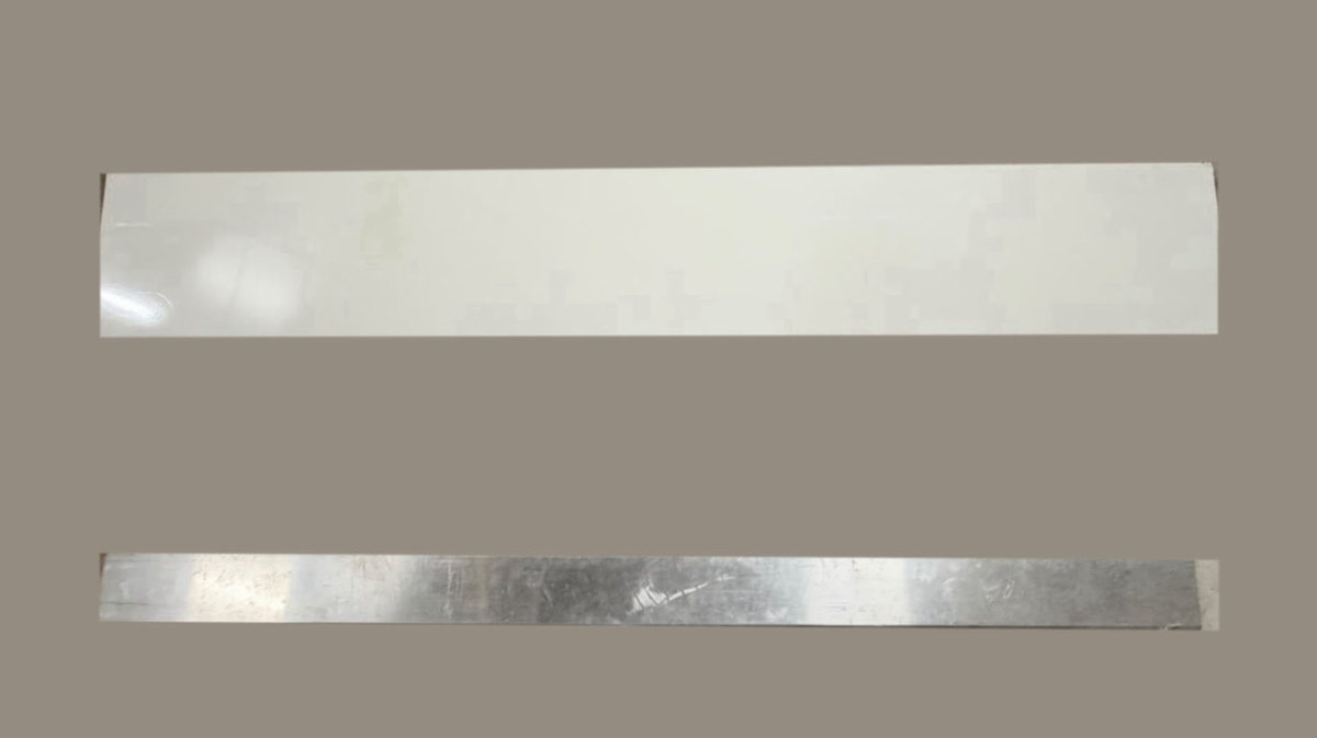 Deux profilés de couronnement sur fond gris uni : en haut un profilé thermolaqué blanc et lisse, en bas un profilé en aluminium brut brillant et marqué